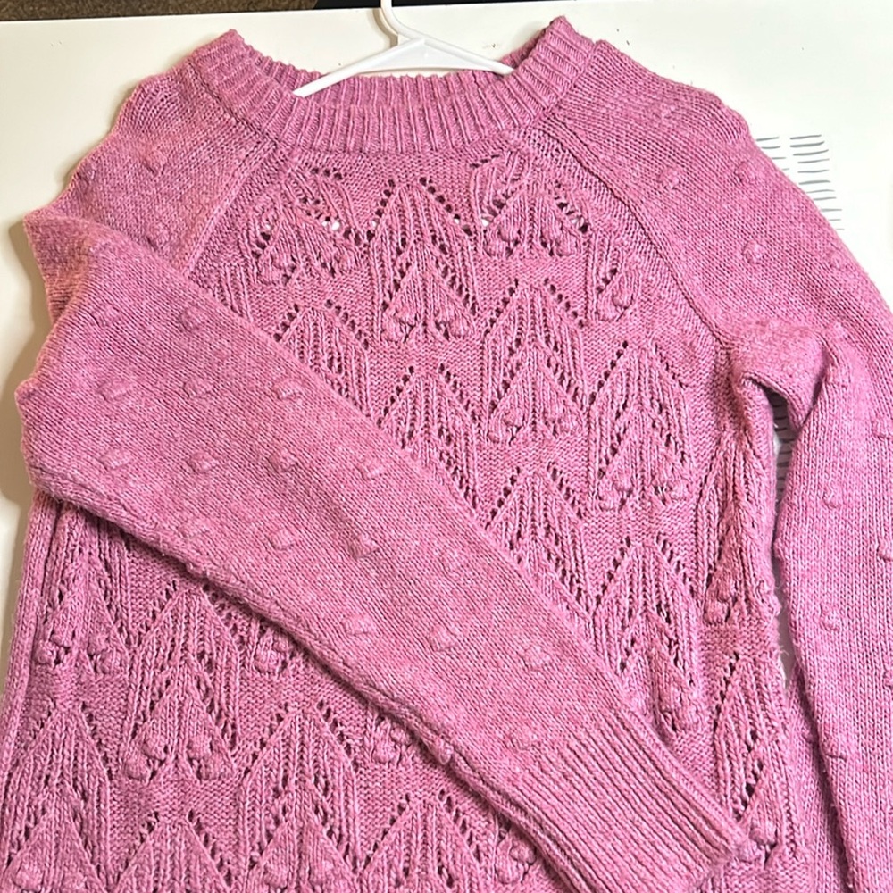 Pink knitted, see through sweater with knitted circles on sleeves.